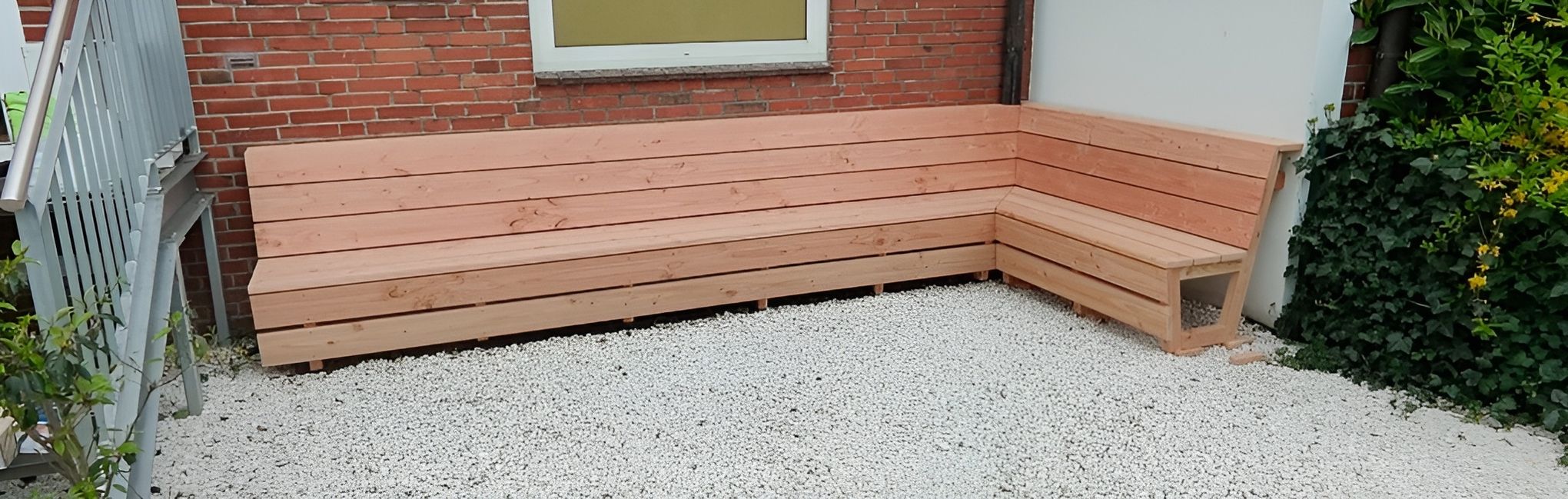 Maßgefertigte Holzbank im Außenbereich vor Backsteinfassade